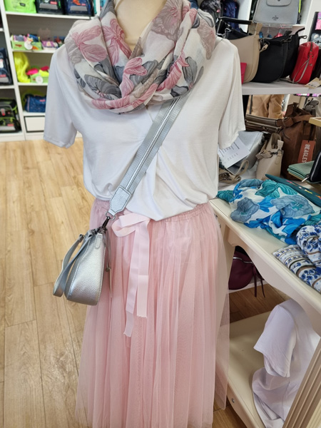 Schaufensterpuppe in modischem Outfit: weißes T-Shirt, rosafarbener Tüllrock, floraler Schal, silberne Tasche.