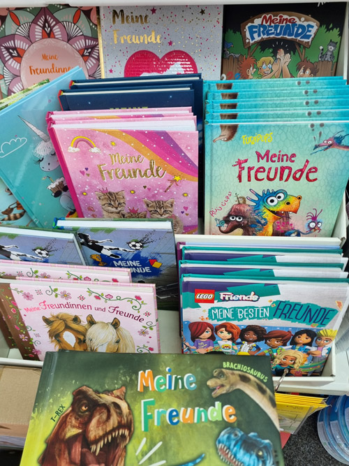 Bunte Freundebücher in einem Regal, mit glitzernden Covern, die fröhlich und kindgerecht wirken.
